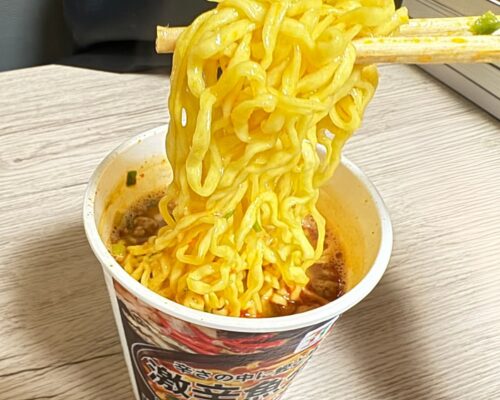 激辛魚介豚骨ラーメンを箸で持ち上げてる写真