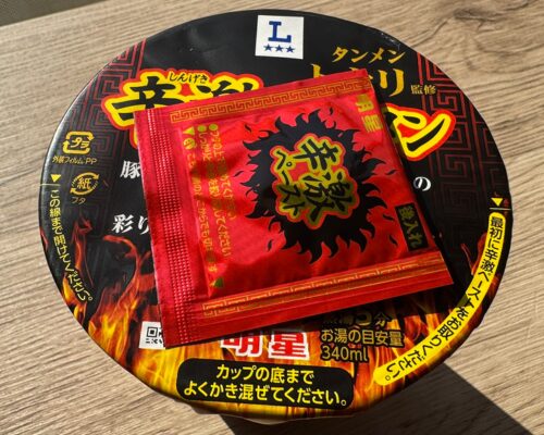 辛激タンメンの蓋の上に置かれた「辛激ペースト」の小袋が写ってる様子